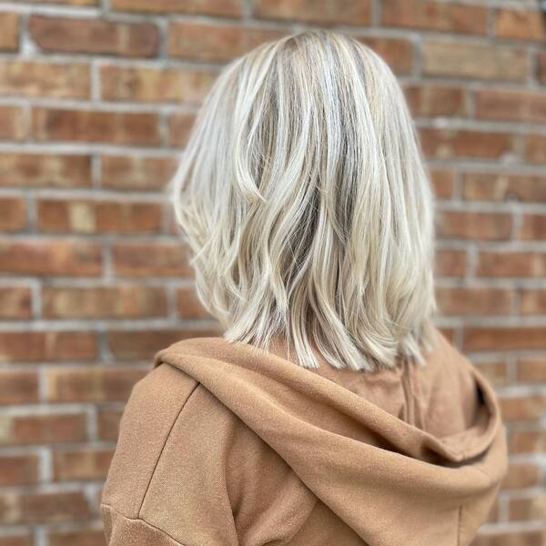 Mid Shaggy Blonde Hairstyle - a woman wearing a brown jacket.