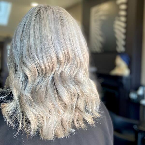 Muted Curls Platinum Blonde Hairstyles - a lady wearing gray sweater.