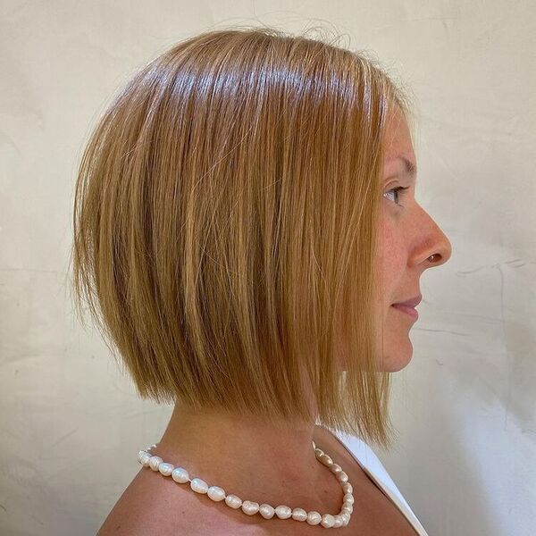 Wild Blunt Haircut- a woman wearing a pearl necklace.